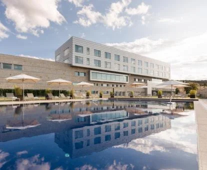 Moderno hotel con piscina y mobiliario exterior.