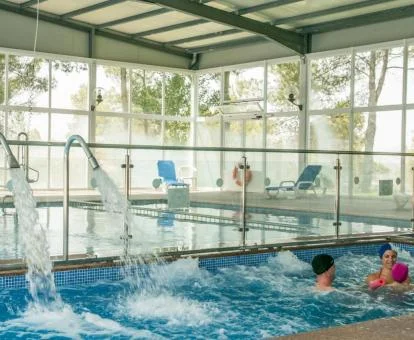 Piscina cubierta con hidroterapia y vistas al exterior del centro de bienestar del hotel.