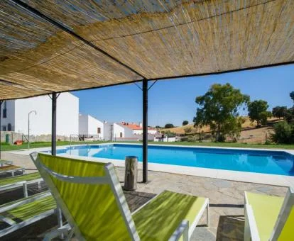 Piscina exterior con tumbonas y jardín del establecimiento.