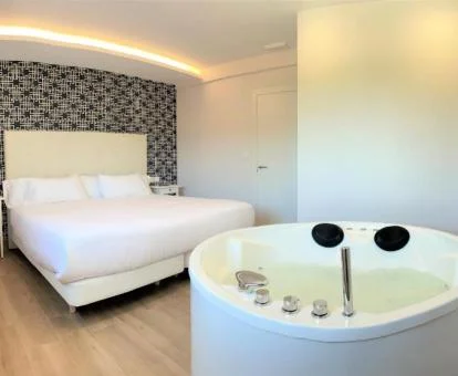 Dormitorio con jacuzzi junto a la cama de uno de los apartamentos del establecimiento.