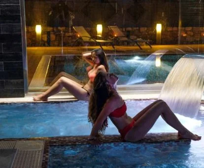 Pareja disfrutando de la piscina con chorros del spa del hotel.