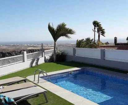 Terraza con piscina al aire libre, tumbonas y vistas a los alrededores de este alojamiento solo para adultos.