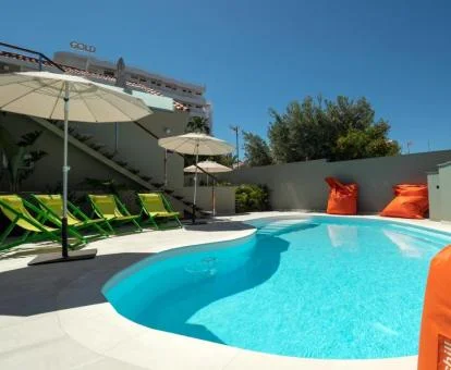 Acogedora piscina exterior de este hotel solo para adultos con tumbonas.