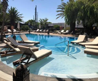 Piscina exterior con solarium y camas sobre el agua de este hotel solo para adultos.
